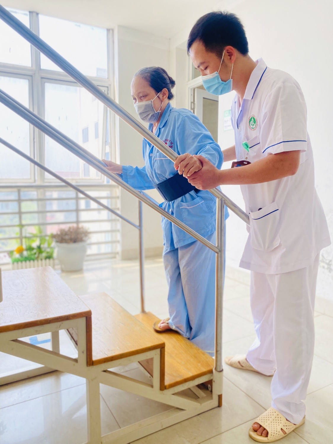 Cán bộ y tế hỗ trợ vận động cho bệnh nhân tại Trung tâm y tế huyện Cẩm Khê